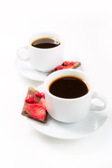 Two cups of coffee and hand-made chocolate with dried strawberries and berries on a white background