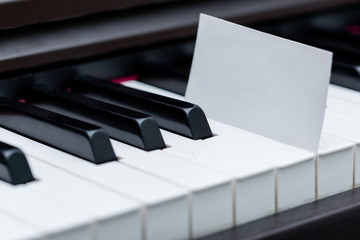 Blank business card placed between piano keyboard racings