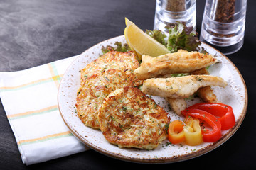 Fried fish with zuccini pancakes and fresh vegetables