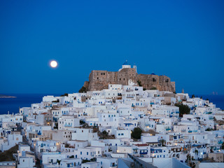 Fototapeta na wymiar Chora of Astypalaia in blue hour and the full moon rising from the horizon