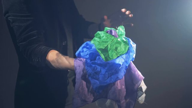 An illusionist is showing a trick with a lot of scarves appearing one after another