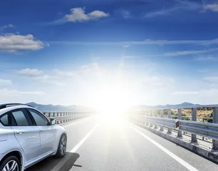 Crédence de cuisine en verre imprimé Voitures rapides Une voiture blanche se précipitant le long d& 39 une autoroute à grande vitesse au soleil.