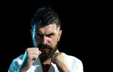 Portrait karate man in white kimono in fighting stance, closeup. Karate, judo, aikido, taekwondo - oriental single combat. Strong, sporty, aggressive, confident, energetic instructor taekwondo.