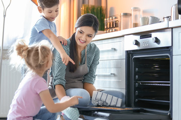 Woman treating children to cookies indoors. Fresh from oven