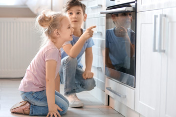 Fototapeta na wymiar Little kids sitting near oven indoors