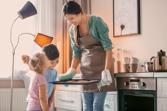 Woman treating children to cookies indoors. Fresh from oven