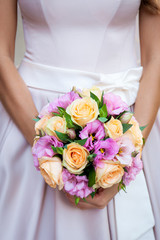 Obraz na płótnie Canvas Wedding flowers. Beautiful fresh little new round bouquet of different colors. The bride in the background. Beautiful photo for web sites and postcards.
