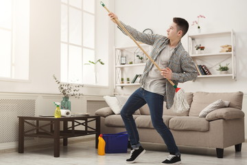 Young man cleaning home, playing with mop