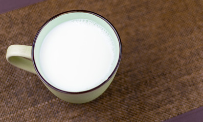 A large cup of milk on a brown background.