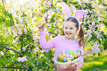 Child with bunny ears on garden Easter egg hunt