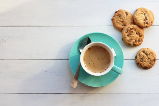 Coffee in a turquoise mug and cookies on a white table the top view