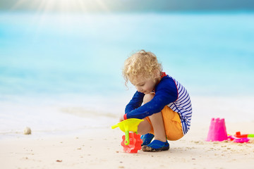 Kids play on tropical beach. Sand and water toy.