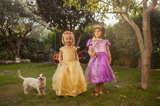 Children in princess costumes playing in the garden. Outdoors.