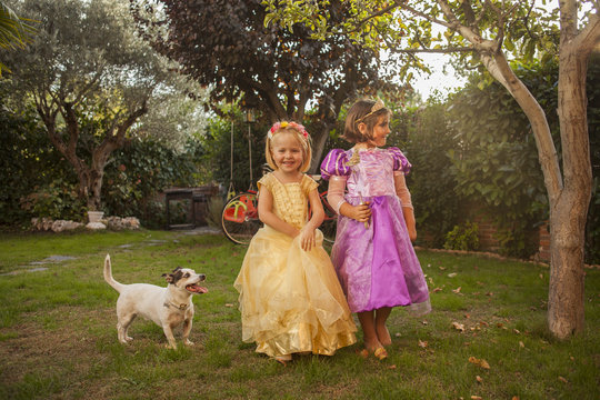 Children in princess costumes playing in the garden. Outdoors.