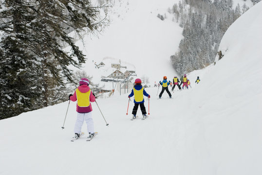 holiday: children, boy and girl, skiing on slope, do a ski lesson during a snowy day, all fresh snow on tree, forest, after a snowfall, winter, cold, Alps, Vigezzo Valley, Italy