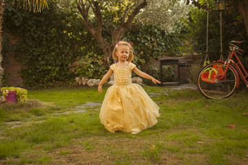 Girl in a princess costume playing in the garden. Outdoors.