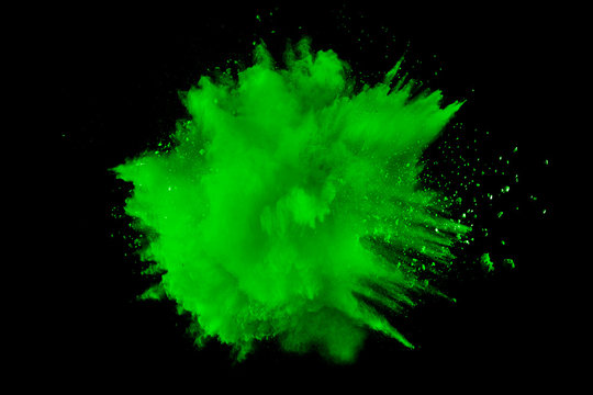 abstract green dust explosion on  black background.abstract green powder splattered on black background.Freeze motion of green powder exploding.