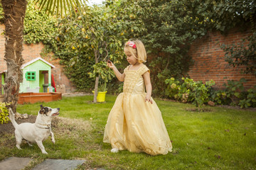 Obraz na płótnie Canvas Kid dress up as a princess playing with a dog. Outdoors.
