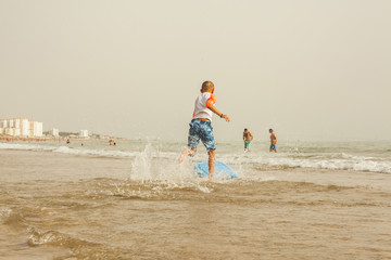 Kid running to catch waves with a board. Surfing in the beach