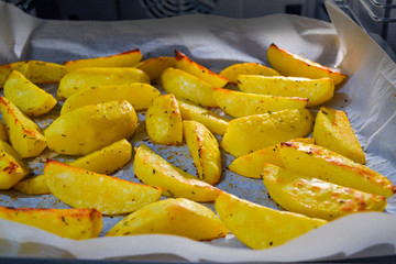 Baked potato wedges in oven on baking paper. Close-up