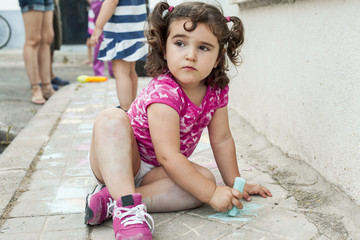 Fototapeta premium Kid painting with chalk in the sidewalk of the road. Outdoors
