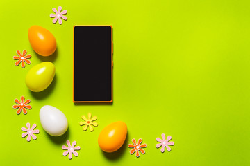 Smart phone and Easter decor on green background