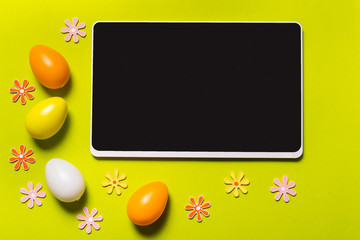 Digital tablet and Easter decor on green background