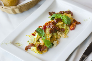 Raw food salad of fresh vegetables and sun-dried tomatoes in a white plate on the table