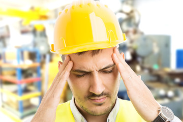 Stressed factory worker suffering head pain migraine or headache.