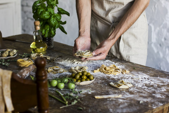 The young man in an apron preparing homemade pasta