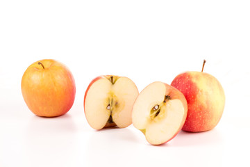 zwei Äpfel und ein geteilter Apfel vor weißem Hintergrund