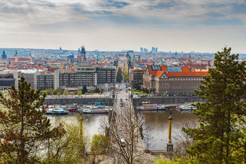 Scenic aerial view of the Old Town architecture and bridge over Vltava river in Prague, Czech Republic. Trees of the park at the foreground.
