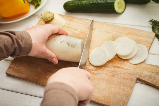 Woman cutting fresh turnip on wooden board