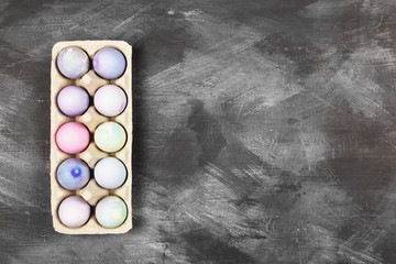 Multi-colored eggs for Easter in container for eggs on black background. Top view, copy space. Food background