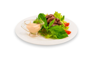 Meat roasted in a sauce with green leaves salad, tomatoes with a cup for sauce on a white plate. Clipping path.
