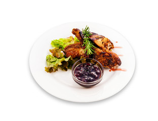 Fried pork ribs with seasonings greens and berry sauce on a white plate. Clipping path of the plate.