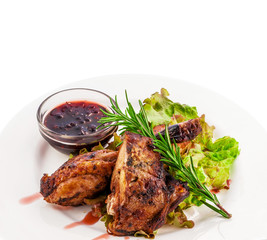 Fried pork ribs with seasonings greens and berry sauce on a white plate. Clipping path of the plate.