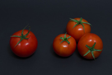 Red tomatoes on a dark background. Four red tomatoes on a dark background.