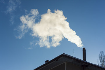 smoke coming out of house chimney. blue sky background