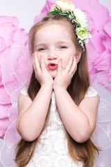 Obraz na płótnie Canvas Little fairy girl in white dress on a background of flowers. Photo taken in studio
