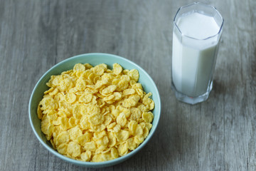 corn flakes are poured into a green plate, and next is a glass of milk, breakfast