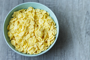 flakes lie on a green plate that stands on a wooden table, breakfast, in the photo there is a place under the text