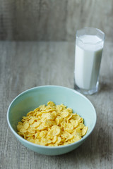corn flakes are poured into a green plate, and next is a glass of milk, breakfast