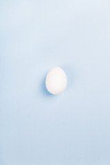 White egg on blue background. Top view