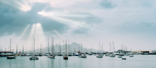 Sailboats and pleasure boats in the porto grande bay of the historic city Mindelo. Sunrays