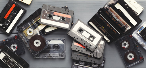 Heap of vintage audio cassettes at gray planks background