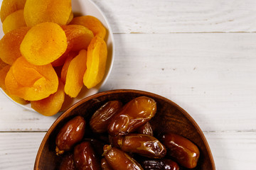 Dried apricots and dates fruit on white wooden table. Top view