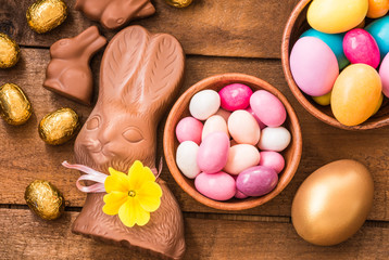 Easter chocolate candy eggs, chocolate bunny on wooden table. Easter holidays food background.