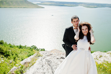 Wedding couple at breathtaking landscape with rock and lake.