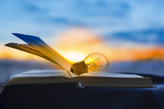 the lamp rests on an open book, knowledge is light.